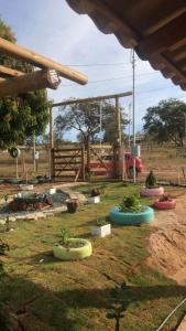 un groupe de plantes en pot dans une cour avec une aire de jeux dans l'établissement Chácara do Cardoso, à Três Marias