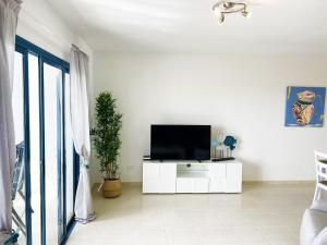 a living room with a television on a white cabinet at LOS CHARCOS TERRACE VIEW in Costa Teguise