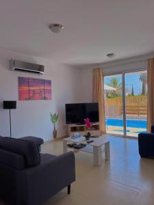 a living room with a couch and a tv and a table at 3 Bedroom Coral Bay Beach Seaview Villa II Private Pool in Coral Bay