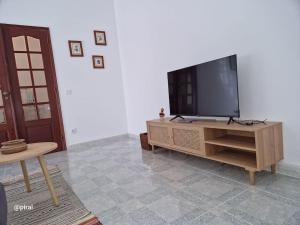 sala de estar con TV de pantalla plana en un centro de entretenimiento de madera en Casa Almeida - Castelo Branco, en Castelo Branco