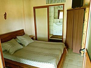 a bedroom with a bed and a bathroom at Hôtel restaurant le MIAMIAM GLOUGLOU in Ambositra