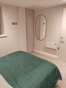 a bedroom with a green bed and a mirror at Central Leeds modern 1bed apartment in Leeds