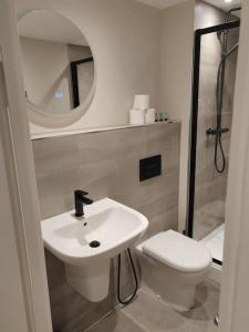 a bathroom with a sink and a toilet and a mirror at Central Leeds modern 1bed apartment in Leeds