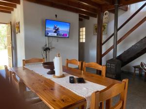 a dining room table with a television on the wall at Cabaña EL GALLO in Villa General Belgrano