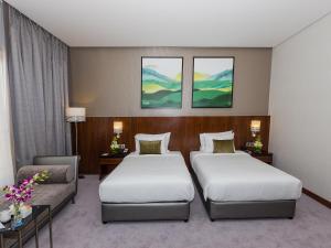 a hotel room with two beds and a couch at Flora Al Barsha Hotel At The Mall in Dubai