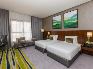 a hotel room with two beds and a couch at Flora Al Barsha Hotel At The Mall in Dubai