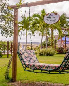 a swing in a park with palm trees and a sign at Eco Resort Pedra Bonita in Santo Estêvão