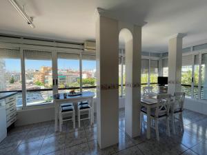 uma cozinha com mesa, cadeiras e janelas em Apartamento a un minuto de la playa de Levante em Benidorm