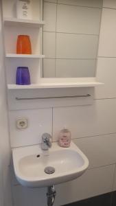 a white sink in a bathroom with shelves at Pension Bad Soden / Apartment and Rooms in Bad Soden am Taunus