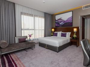 a hotel room with a large bed and a desk at Flora Al Barsha Hotel At The Mall in Dubai