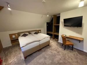 Schlafzimmer mit einem Bett, einem Schreibtisch und einem TV in der Unterkunft Berggasthof Tönsblick in Oerlinghausen