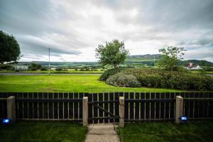 a wooden fence in front of a green field at Binevenagh View, Magilligan Holiday Let in Limavady