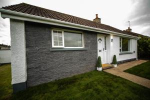a brick house with a window and a grass yard at Binevenagh View, Magilligan Holiday Let in Limavady
