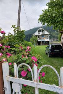 a white fence with pink flowers in front of a house at Bombora in Mestia