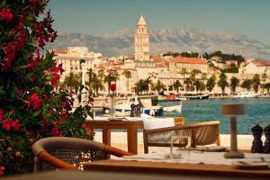 a restaurant with tables and chairs next to a body of water at Hotel Ambasador in Split