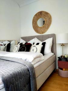 una camera da letto con letto, cuscini e specchio di UNIQUE BEIGE & GOLD Apartments a Kołobrzeg