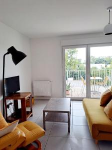 a living room with a couch and a table at Logement neuf dans résidence calme parking gratuit in La Rochelle