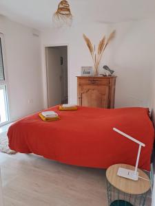 a large red bed in a white room with a table at Logement neuf dans résidence calme parking gratuit in La Rochelle
