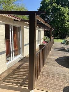 a wooden boardwalk leading to a house with a wooden pergola at Maison sous les chênes in Le Gua