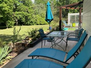 a patio with a table and chairs and an umbrella at Maison sous les chênes in Le Gua