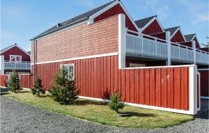 un edificio rojo con árboles delante de él en Stunning Home In Blvand With 2 Bedrooms, Sauna And Wifi, en Blåvand