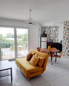 a living room with a couch and a table at Logement neuf dans résidence calme parking gratuit in La Rochelle