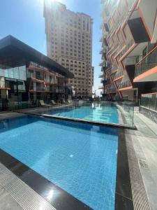 a large swimming pool in a city with tall buildings at Vibrant 2 Bedroom - E&G Homes in Dubai