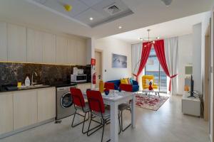 a kitchen and living room with a table and red chairs at Vibrant 2 Bedroom - E&G Homes in Dubai