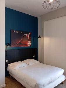 a bedroom with a large bed with a blue wall at Nemea Appart Hotel Coliseum Amiens Centre in Amiens