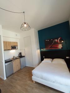 - une chambre avec un lit blanc et un mur bleu dans l'établissement Nemea Appart Hotel Coliseum Amiens Centre, à Amiens