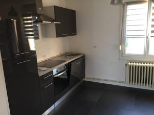 a kitchen with black cabinets and a sink and a window at Appartement f3 au calme in Florange