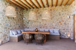 a table and chairs in a room with a stone wall at Luxusvilla Lagoon 4 Personen privater Pool in Gialova