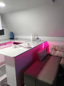 a kitchen with a table and a bench with pink lighting at Doğa içinde ferah yaşam in Mugla