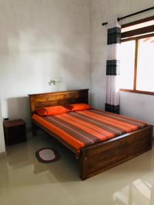 1 dormitorio con cama con sábanas de color naranja y ventana en Sanithu Homestay Galle en Galle