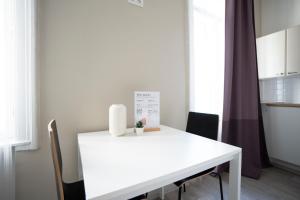 Una mesa blanca en una habitación con sillas y una cocina. en Bright ,cozy , central and cute studio in Vienna, en Viena