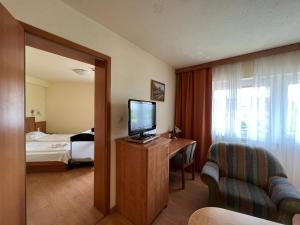 Habitación de hotel con TV y dormitorio en Aqua Therm Hotel, en Zalakaros