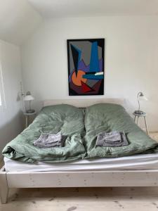 a bed with a green blanket and two pillows at Ferielejlighed på Elmensbjerg in Asperup