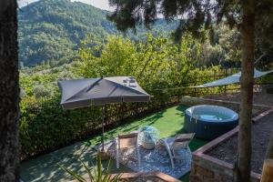 a table and chairs with an umbrella and a hot tub at Poggio al Mandorlo in Greve in Chianti