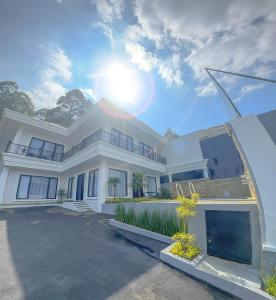 a large white house with the sun in the sky at Villa London Puncak in Sampal 2