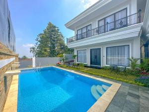 a swimming pool in front of a house at Villa London Puncak in Sampal 2
