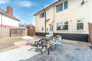 a patio with chairs and a table in front of a house at Aseda 4 BedRoom Private Parking, Game Zone -Pool table, Garden Home in Hull