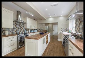 a large kitchen with white cabinets and wooden floors at Stubbs House, Loddon, sleeps 20, 2 hot tubs in Loddon