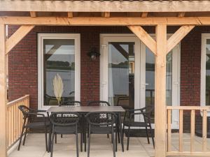 un patio con mesa y sillas en un porche en Lakeview villa with swimming and fishing pier, en Simonshaven