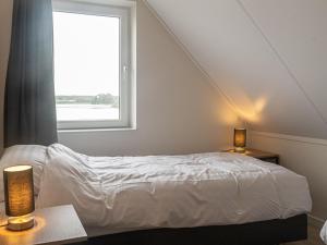 1 dormitorio con cama y ventana en Lakeview villa with swimming and fishing pier, en Simonshaven