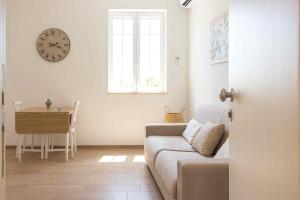 a living room with a couch and a table and a clock at Boga & Vopa House in Savelletri di Fasano
