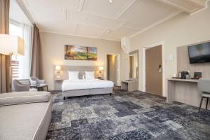 Habitación de hotel con cama blanca y TV en Fletcher Hotel Landgoed Huis te Eerbeek, en Eerbeek