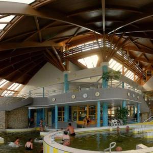 a large building with a swimming pool and people in it at Green Penthouse in Tiszaújváros