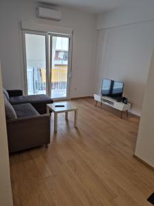 a living room with a couch and a tv and a table at New house in Pireas port in Piraeus