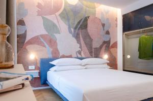 a bedroom with a white bed and a colorful wall at Neró Rooms in Taormina