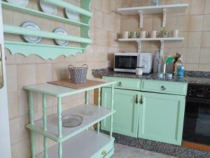 cocina con armarios verdes y microondas en En el Parque de las Meanas., en Avilés 8 fotos más